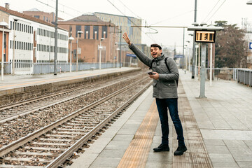 Man waving at train station during cloudy day