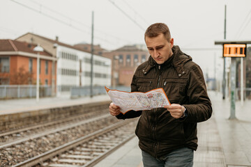 Traveler examines map at train station on a cloudy day