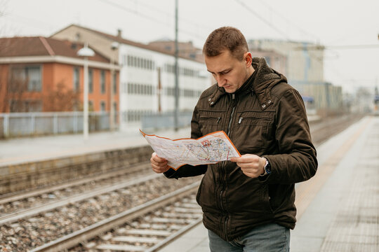Man studying a map at a train station on a cloudy day