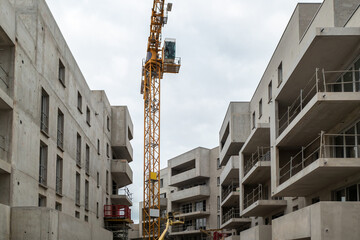 Desenvolvimento urbano com novos edifícios de concreto em fase de construção avançada com uma grua a meio num dia muito nublado