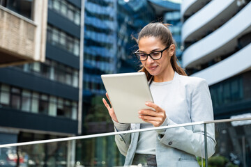 Professional woman standing confidently outside modern office building, interacting with digital...