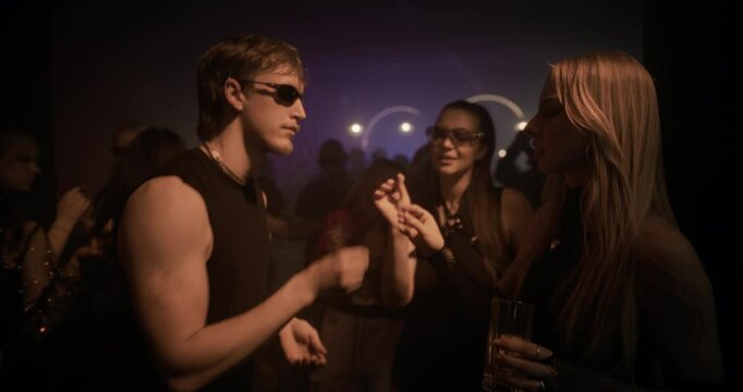 Close Up of Two Young Female Receiving Small Party Pills from a Male Friend. Friends Smile and Dive Into the Music, Dancing with Renewed Excitement, Expressing Energy and Joy