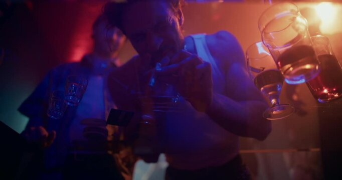 Cinematic Shot From Beneath a Glass Surface as Two Partygoers Bend Over the Table and Inhale Drugs or Prescription Stimulants in a Nightclub. Dynamic, Nightlife Moment in the Middle of the Party
