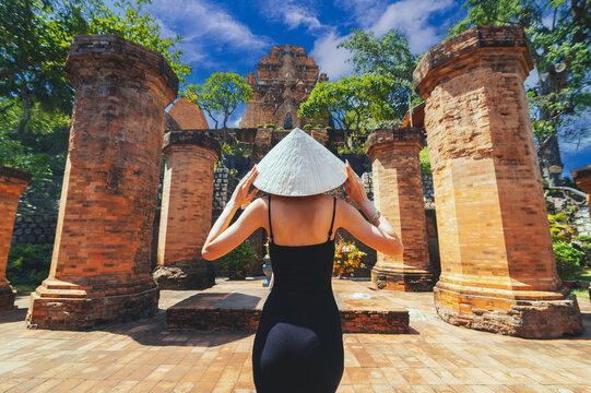 A female tourist stands with her back against the background View of Po Nagar Cham towers complex.