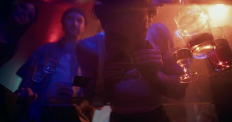Staged Low-Angle Party Footage with Two Male Friends Leaning Over a Glass Table in Order to Snort Cocaine, Viewed From Below. Flashing Lights and Electronic Music Set a Wild, High-Energy Atmosphere - Powered by Adobe