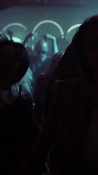 Vertical Screen: Creative People Move to Techno in a Dark, Color-Drenched Club with Flashing Stroboscopes. Cinematic Slow Motion Footage Celebrating Nightlife, Youth Culture, Freedom and Urban Energy