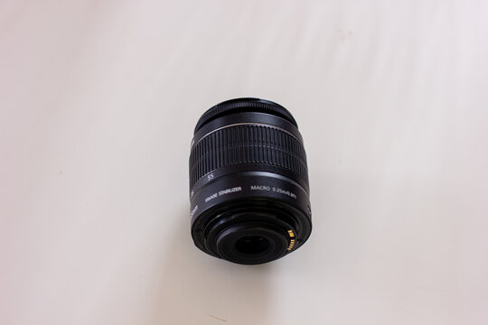A black camera zoom lens standing on a white background. Photography equipment, technology, and photographer's gear concept - Powered by Adobe