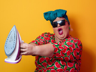 Playful plus size woman aiming iron like weapon in sunglasses