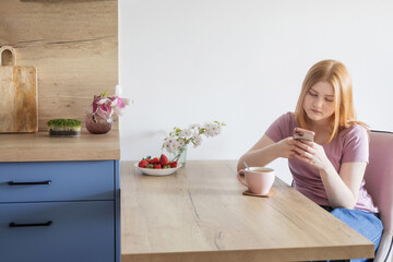 young blonde woman with cup of tea on the kitchen