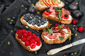 Bruschetta with labneh, prosciutto, salami, figs, peaches, cherry tomatoes, basil, and fresh berries. Rustic Italian-style appetizers with creative toppings