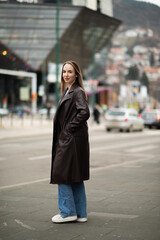 Stylish woman posing in leather coat on city street