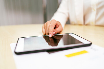 Close-up of a business professional using a digital tablet on a desk, focusing on touchscreen interaction, digital workflow, and paperless productivity in a modern office setting.