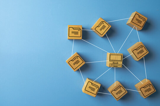 A central computer on a wooden block connected to a network of file folder icons. Concept for a Document Management System (DMS), file sharing,file storage, data management,cloud storage.