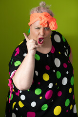 Plus size woman in vibrant polka dot outfit making a comic shrug gesture with outstretched hands and amusing expression.