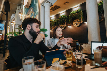 Business colleagues communicating over coffee at a cafe, exchanging ideas using laptops and papers. Capturing a blend of teamwork and collaboration in a relaxed environment.