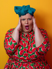 Plus size woman smiling and touching head in watermelon dress