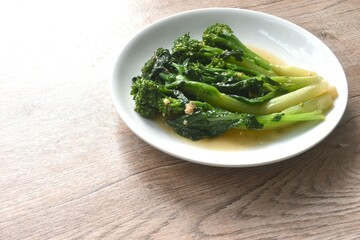 fried Kailaan Chinese kale dressing oyster sauce with chop garlic and salty fish on plate