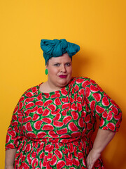 Plus size woman smiling and touching head in watermelon dress