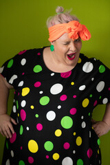 Plus size woman in vibrant polka dot outfit making a comic shrug gesture with outstretched hands and amusing expression.