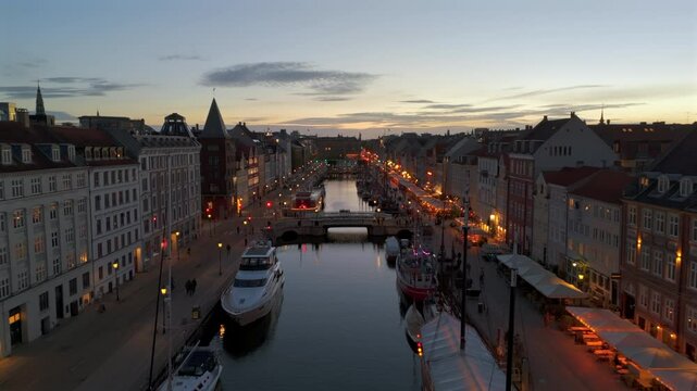 Aerial view of the historic Nyhavn waterfront, a 17th-century canal and entertainment district lined by brightly coloured townhouses, bars and restaurants, at dusk in Copenhagen, Denmark.	

