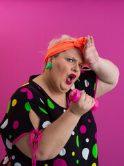 Surprised plus size woman exercising with pink dumbbells on colorful background