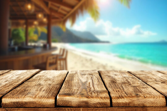 Empty wooden table with open space for product placement or branding. In the background blurred summer scene with sandy coastline and beach cafe and the blue sea under sunny sky.