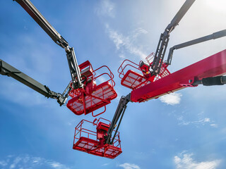 Workers operating lift equipment under clear blue sky during outdoor construction activity near urban area