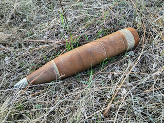 Explosive shell resting in grassland after a conflict, highlighting dangers of unexploded ordnance in rural areas