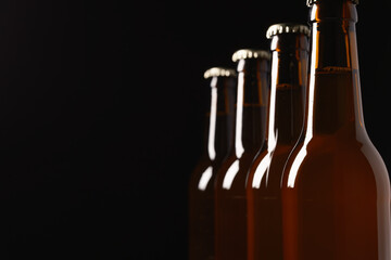 Four craft beer bottles in a row with black background and copy space.