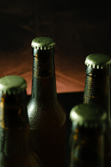 Close-up of chilled beer bottles with condensation in dark moody lighting.