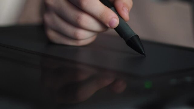 hand of a child drawing with a stylus on a graphic tablet, processing photos and creating paintings on a graphic tablet