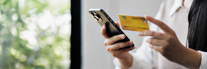 Young woman using credit card with mobile phone to complete purchase through secure online platform