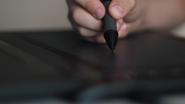 hand of a child drawing with a stylus on a graphic tablet, processing photos and creating paintings on a graphic tablet