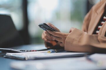 Fototapeta premium Young beautiful Asian businesswoman holding smartphone while working in the office room.