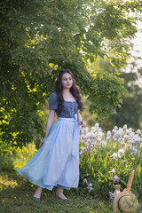 A girl in a beautiful dress with irises in the garden