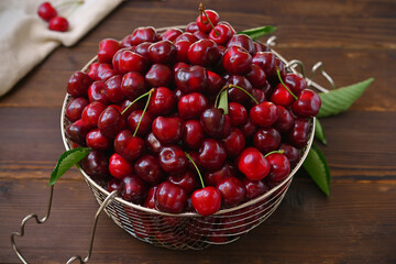 colander full of ripe cherries on wooden table