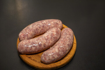 Meat sausages prepared for grill on a wooden board. Raw sausages for grill.