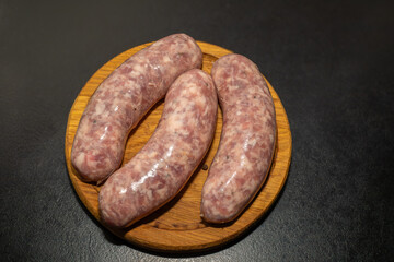Meat sausages prepared for grill on a wooden board. Raw sausages for grill.