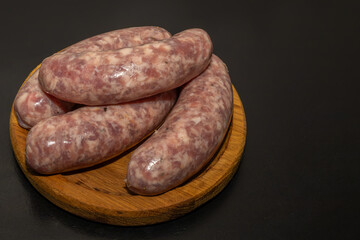 Meat sausages prepared for grill on a wooden board. Raw sausages for grill.