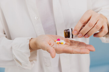 Female pouring pills from a medicine bottle into hand