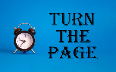 Turn the Page symbol. Concept words Turn the Page on Beautiful blue background with alarm clock. Business and Turn the Page concept. Copy space.
