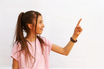 Attractive happy teenage girl with fitness bracelet pointing finger to the side on white background