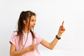 Attractive teenage girl with fitness bracelet pointing finger and looking away on white background