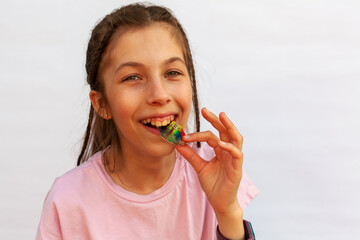 Happy girl in pink t-shirt putting orthodontic plate on teeth with uneven teeth, malocclusion on white background. Concept orthodontic treatment
