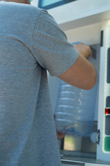 Man at clean water vending machine practicing daily health care routine in urban environment.