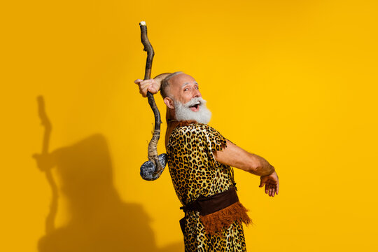 Portrait of primeval caveman hold stone ax wear leopard skin clothes isolated on yellow color background