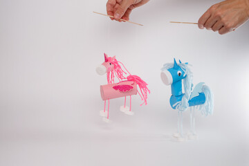 Unicorn puppets made from recycled materials in hands on white background perfect for kids craft...