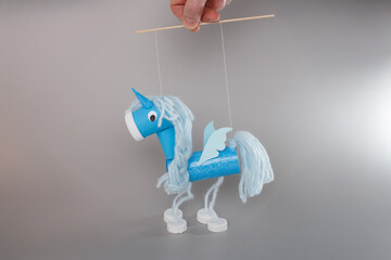 Eco-friendly unicorn marionettes held by hands on white background great for blogs about...