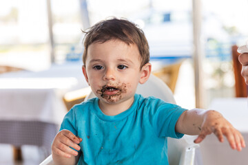 Toddler eating black rice stained with squid ink at restaurant