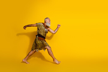 Full length photo of funny strong cave human wear leoprad skin running emtpy space isolated yellow color background